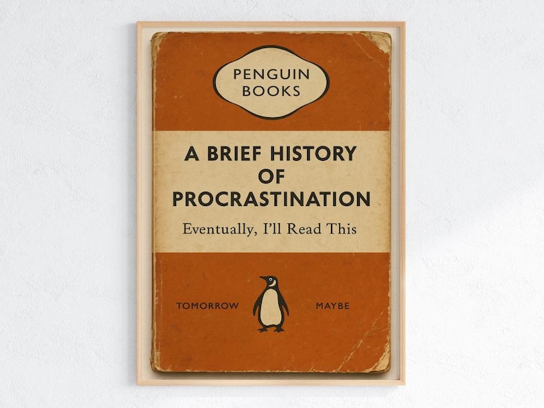 以下が含まれることがあります： ペンギンブックスの「A Brief History of Procrastination」というタイトルの本の表紙の額入りプリント。表紙はオレンジとクリーム色で、ペンギンのイラストが描かれています。「Eventually, I'll Read This」、「Tomorrow」、「Maybe」というテキストが含まれています。
