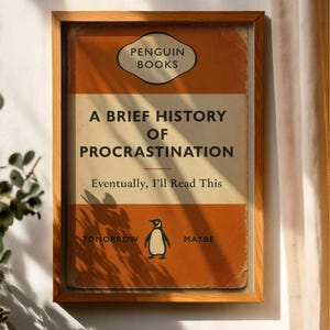以下が含まれることがあります： 「A Brief History of Procrastination」というタイトルのペンギンブックスの書籍カバーの額装プリント。オレンジと白のカバーには、ペンギンのイラストと「Eventually, I'll Read This」と「Tomorrow Maybe」のテキストが記載されています。
