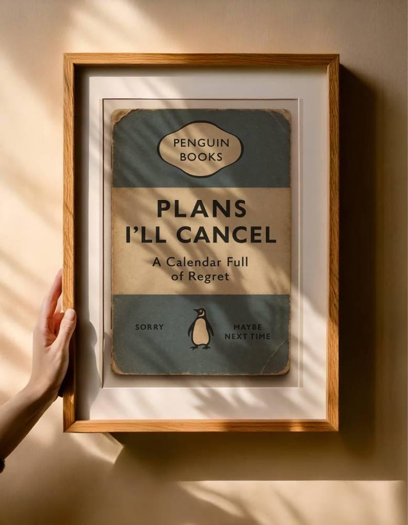 May include: Framed print with a vintage Penguin Books design. The print reads "PLANS I'LL CANCEL" with a penguin illustration. The frame is a light brown wood, and the print has a distressed, aged appearance.