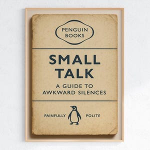 May include: A framed print of a book cover titled "Small Talk: A Guide to Awkward Silences" by Penguin Books. The cover is beige with navy blue text and a penguin illustration. The frame is a light wood color.
