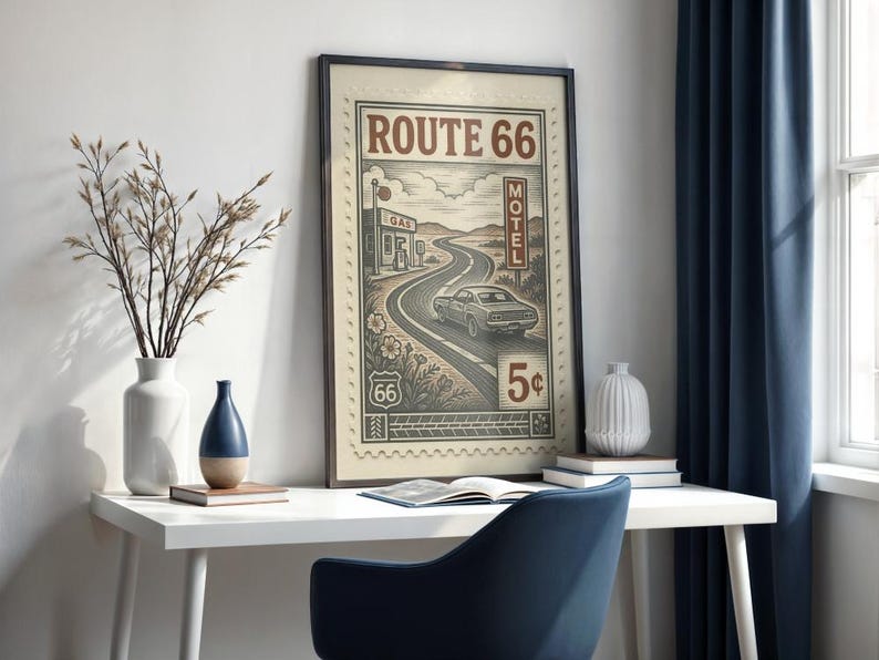May include: A framed Route 66 art print. The vintage-style artwork features a winding road, a classic car, and the text "Route 66." The print is displayed on a white desk with decorative vases and a blue chair. The artwork is approximately 18 x 24 inches.