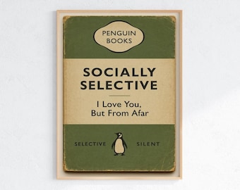 Peut inclure: Impression encadrée avec un design de couverture de livre de style vintage. La couverture est principalement verte et beige, avec le titre "Socialement sélectif" et la phrase "Je t'aime, mais de loin". Une illustration de pingouin est présente.