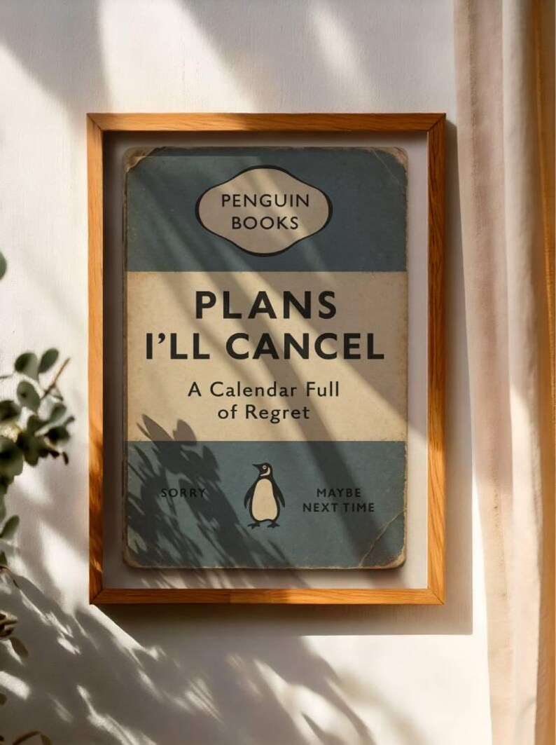 May include: A framed print of a book cover with the title "PLANS I'LL CANCEL" and the Penguin Books logo. The cover is blue and beige with a penguin illustration. The text "A Calendar Full of Regret" is also visible.