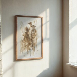 May include: Abstract watercolour painting of three figures in cowboy hats, framed in natural wood. The artwork features shades of brown and beige, creating a rustic aesthetic. The framed art is displayed on a white wall.