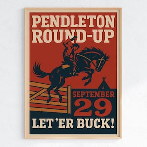 May include: A framed vintage poster for the Pendleton Round-Up rodeo event. The poster features a cowboy riding a bucking horse over a fence, with text that reads "Pendleton Round-Up," "September 29," and "Let 'Er Buck!"