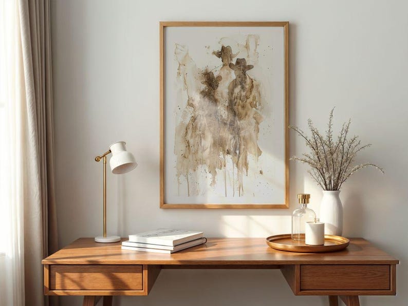 May include: Abstract art print in a wooden frame, featuring a brown and beige watercolour design of figures wearing hats. The print is above a wooden desk with a white lamp, books, and decorative items.