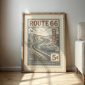 May include: Framed Route 66 art print. The artwork features a vintage car driving on a winding road, with a gas station and motel sign. The design is in shades of brown and beige, resembling a postage stamp.