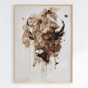 May include: A watercolour painting of a bison's head in brown and sepia tones. The artwork shows a detailed depiction of the animal's face, horns, and fur, with paint drips adding texture. The artwork is framed in a light-coloured wooden frame.