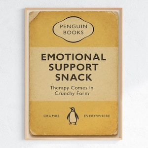May include: A framed print with a retro design. The image has a yellow and tan background with the text "EMOTIONAL SUPPORT SNACK" and "Therapy Comes in Crunchy Form." A penguin illustration is at the bottom.