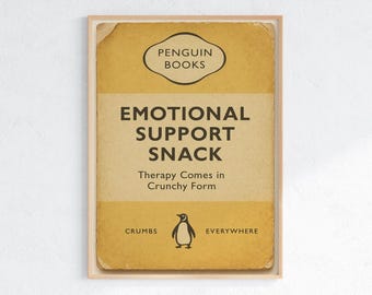 Peut inclure: Une affiche encadrée au style vintage. Le design présente un fond jaune et beige avec les mots "EMOTIONAL SUPPORT SNACK" et "Therapy Comes in Crunchy Form". Une illustration de pingouin est en bas.