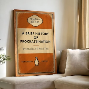 以下が含まれることがあります： ペンギンブックスの「A Brief History of Procrastination」というタイトルの本の表紙の額入りプリント。表紙はオレンジとクリーム色で、ペンギンのイラストが描かれています。テキストは「Eventually, I'll Read This」と「Tomorrow Maybe」と書かれています。