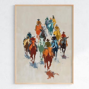 May include: An abstract painting depicting a group of cowboys on horseback, painted in a loose, impressionistic style. The riders are in various colours, including orange, blue, and yellow, against a neutral background. The artwork is framed in a light wood.