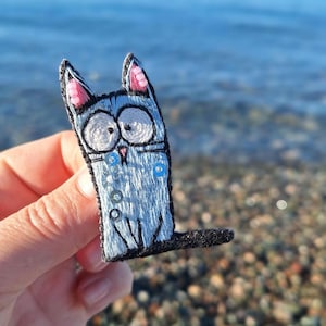 Surprised Dreamer Cat - Hand-Embroidered Gray-Blue Brooch, Whimsical Cartoon Pin. Gift for her.