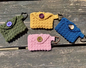 Szydełkowana kieszonkowa torebka z brelokiem w kształcie serca od Campfire Crochet. Wykonana w Wielkiej Brytanii z przędzy z recyklingu i guzików z recyklingu, każdy egzemplarz jest wyjątkowy.