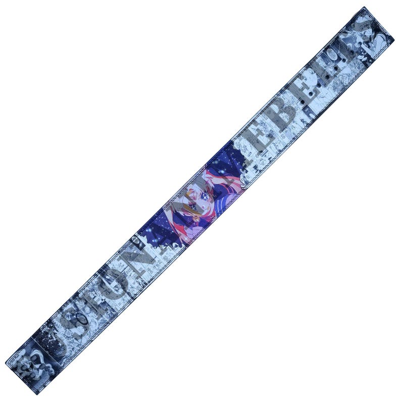 Pu&ograve; includere: Una lunga sciarpa rettangolare con un'illustrazione in stile manga di una donna con i capelli rosa e un abito blu e viola. La sciarpa ha uno sfondo blu e bianco con la parola "EBBE" stampata sopra.