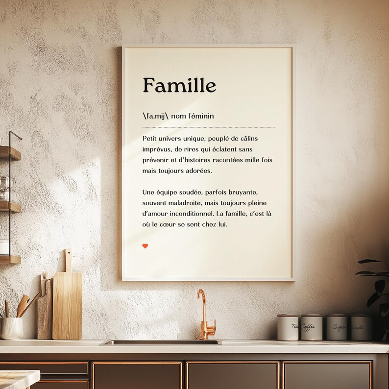 May include: A framed print with a white background and black text. The text reads "Famille" and defines the word as a small, unique universe filled with spontaneous hugs, laughter, and cherished stories. It describes a family as a close-knit team, sometimes loud, often clumsy, but always full of unconditional love.