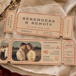 May include: Two vintage-style wedding invitation tickets with a cream background and red accents. The top ticket reads "BÉRENGÈRE & BENOÎT" and "12 JUIN 2030/15H". The bottom ticket features a photo of a couple and event details. A wax seal and dried flowers are also visible.