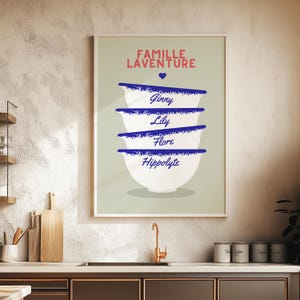 Peut inclure: Une affiche verte et blanche avec le texte "FAMILLE LAVENTURE" en rouge et bleu. L'affiche présente une pile de quatre bols blancs avec des bords bleus, chacun avec un nom écrit en bleu : Ginny, Lily, Flore et Hippolyte.