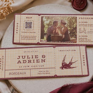 Peut inclure: Deux cartons d'invitation de mariage de style vintage avec une photo d'un couple, un code QR et les noms Julie & Adrien. Les invitations sont marron clair avec des accents bordeaux et une illustration d'hirondelle.