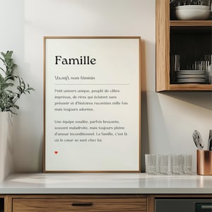 May include: A black and white printable wall art print with the French word "Famille" defined as a unique universe filled with love, laughter, and cherished memories. The print features a small red heart at the bottom.