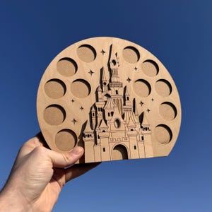 May include: A wooden castle-shaped organiser with 12 circular cutouts, ideal for storing small items such as jewellery or craft supplies. The castle is intricately detailed and features a whimsical design.
