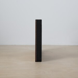 May include: A dark brown wooden frame with a black background.