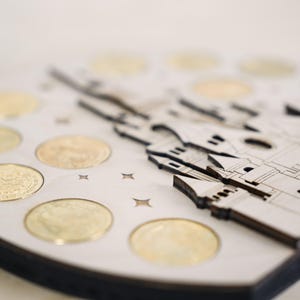 May include: A wooden coin holder shaped like a castle with a white background and gold coins in the slots.