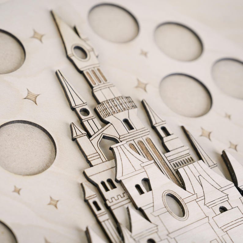 May include: A wooden cutout of a castle with intricate details, set against a background of stars. The castle has multiple towers and windows, and the design is reminiscent of a fairytale.