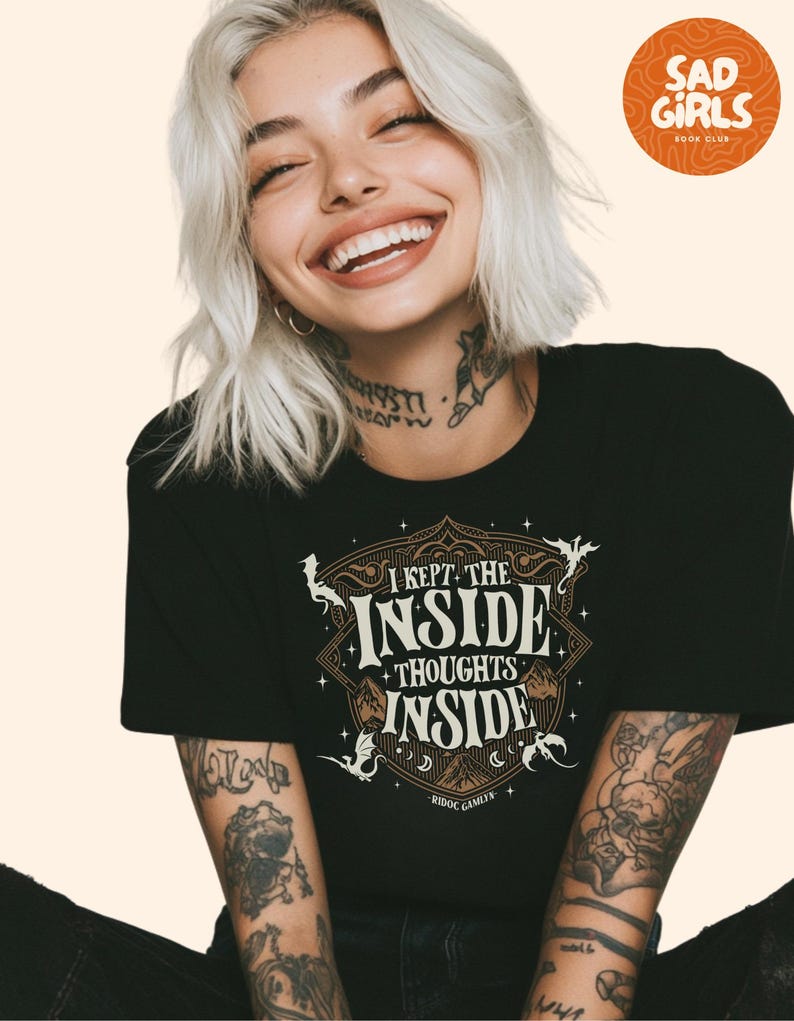 May include: Black t-shirt with the text "I KEPT THE INSIDE THOUGHTS INSIDE" in a decorative design. The shirt also features the text "RIDOC GAMLYN". A round orange logo in the upper right corner reads "SAD GIRLS BOOK CLUB".