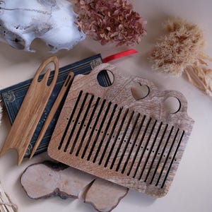 May include: Wooden loom with a heart-shaped cutout, used for weaving small projects. The loom is made of light brown wood and has a series of holes for threading yarn.