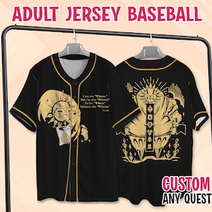 Puede incluir: Una camiseta de béisbol negra con ribetes dorados y estampados gráficos dorados. El frente presenta un personaje similar a un sol y el texto: I too am "Whooo." But I'm also "Wheee!" So the "Wheee" balances the "Whooo." La parte posterior muestra un gran sol.