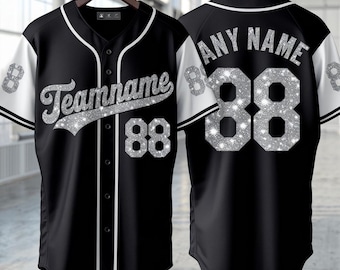 May include: A black baseball jersey with white trim and sleeves, featuring silver glitter text that reads Teamname and the number 88 on the front. The back displays the text Any Name and the number 88 in the same silver glitter style.