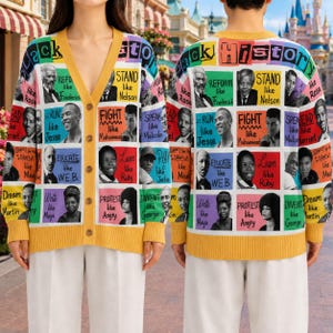 Op de afbeelding: Een vest met lange mouwen en V-hals met een kleurrijk ruitpatroon met portretten van historische figuren en tekst waaronder Black History, Stand like Nelson, Fight like Muhammad en Educate like W.E.B. Het kledingstuk heeft een gele rand.