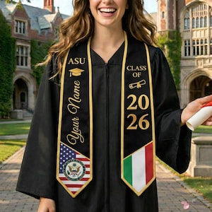 May include: A black graduation gown with a gold-trimmed sash. The sash displays the text "ASU", "Your Name", and "Class of 2026". The sash also features the American flag and a flag with green, white, and red stripes.
