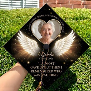 May include: Black graduation cap featuring a photo of a woman within a heart, angel wings, and the name "Natalie" with the class year 2026. The cap includes the quote, "I ALMOST GAVE UP BUT THEN I REMEMBERED WHO WAS WATCHING."