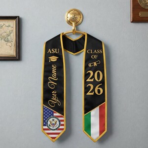 Puede incluir: Una estola de graduaci&oacute;n negra con borde dorado que presenta el texto ASU, Your Name y Class of 2026. El lado izquierdo muestra la bandera de los Estados Unidos con el sello, mientras que el lado derecho presenta la bandera italiana y un icono de diploma.