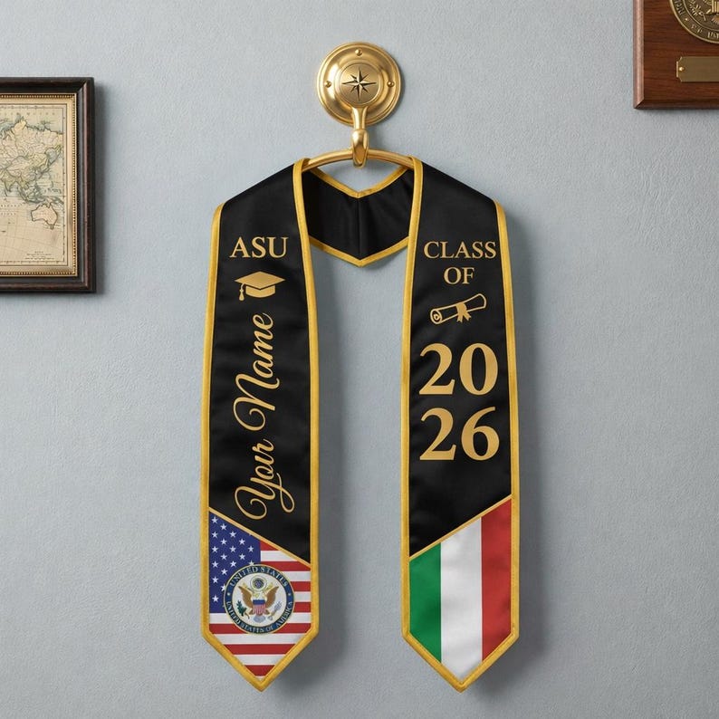 Puede incluir: Una estola de graduaci&oacute;n negra con borde dorado que presenta el texto ASU, Your Name y Class of 2026. El lado izquierdo muestra la bandera de los Estados Unidos con el sello, mientras que el lado derecho presenta la bandera italiana y un icono de diploma.