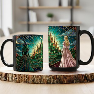 Puede incluir: Dos tazas de cer&aacute;mica negra con un dise&ntilde;o de fantas&iacute;a. Una taza presenta una bruja con un vestido y sombrero verdes, la otra una mujer con un vestido rosa, ambas frente a un castillo. El dise&ntilde;o tiene un efecto de vidriera con un fondo de cielo nocturno.