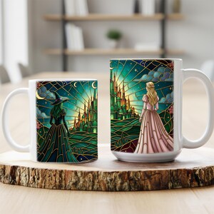Puede incluir: Dos tazas de cer&aacute;mica blanca con dise&ntilde;os de fantas&iacute;a. Una taza presenta una bruja con un vestido oscuro, la otra una princesa con un vestido rosa, ambas mirando un castillo verde bajo un cielo estrellado. Las tazas est&aacute;n sobre una superficie de madera.