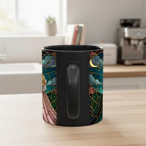 Puede incluir: Taza de cer&aacute;mica negra con un dise&ntilde;o de vidriera que representa a una mujer, la luna y estrellas. La obra de arte incluye tonos de azul, verde, dorado y rosa. La taza tiene un asa y un interior negros, apta para bebidas fr&iacute;as o calientes.