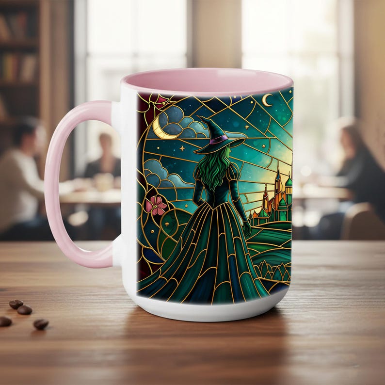 Puede incluir: Taza de cer&aacute;mica blanca con interior y asa rosa. La taza presenta una ilustraci&oacute;n de estilo vidriera de una bruja con vestido y sombrero negros, mirando un castillo bajo un cielo iluminado por la luna. El dise&ntilde;o incorpora tonos turquesa, dorado y rosa.