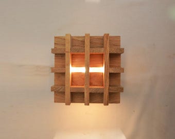 May include: A wooden wall sconce with a grid pattern and a warm light shining through.