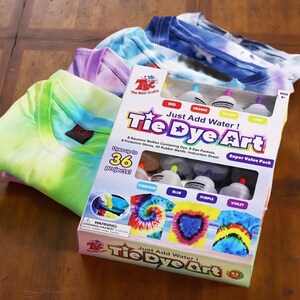 Just Add Water tie-dye art kit with dye bottles and folded T-shirts in pastel and rainbow colors for creative craft projects.