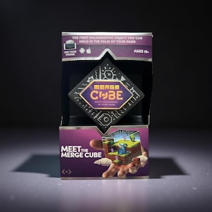 Merge Cube interactive hologram toy in retail packaging, showing a cube that creates 3D holograms when used with a smartphone app.