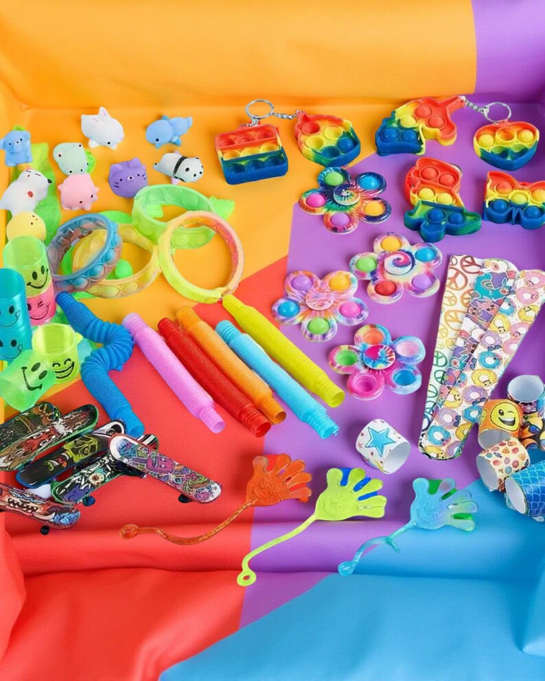 Colorful assortment of fidget toys including pop-its, squishy figures, slap bracelets, stretchy tubes, and sensory items on a bright background.