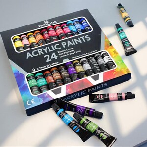 Set of 24 acrylic paint tubes in assorted vibrant colors with brushes, arranged around an open paint box.