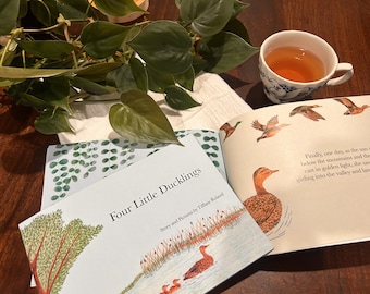 May include: A children's book, "Four Little Ducklings", with illustrations of ducks and a pond. A cup of tea and a leafy green plant are also in the image.