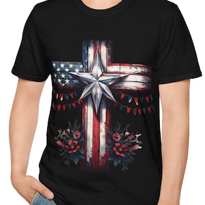 May include: Black t-shirt featuring a cross design with the American flag pattern. The cross has a star in the center and is decorated with red, white, and blue bunting and floral accents. The shirt is made of a soft material.