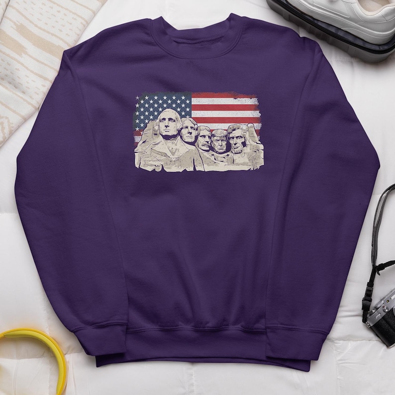 a purple sweatshirt with an American flag design, including the Mount Rushmore monument figures.