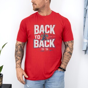 A man wearing a red t-shirt with the text "BACK TO BACK" and a graphic of the Eiffel Tower.